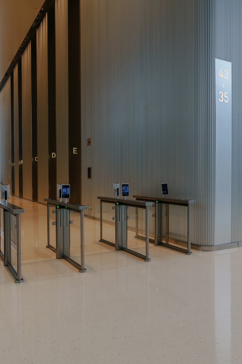 Glazen toegangspoortjes staan in een moderne kantoorlobby.