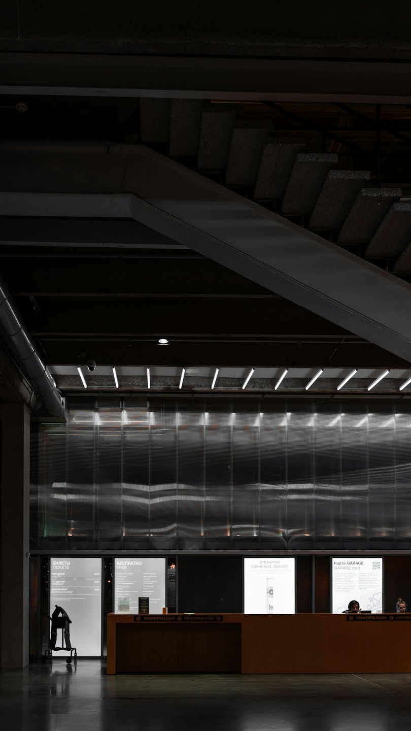 Personeel werkt aan een moderne houten receptiebalie met displaypanelen.