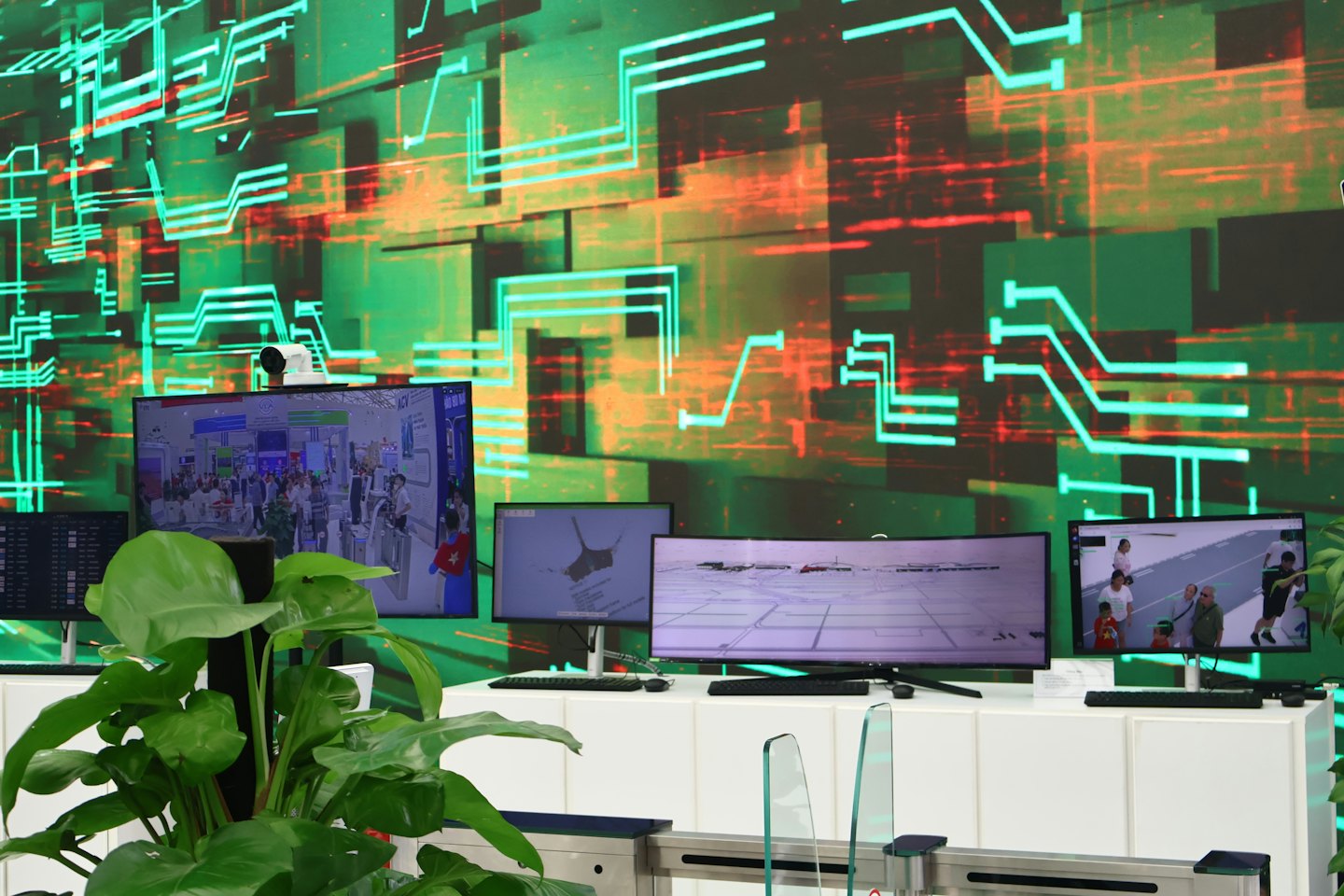 Meerdere digitale schermen tonen beveiligingsbeelden en kaarten in een controlekamer.