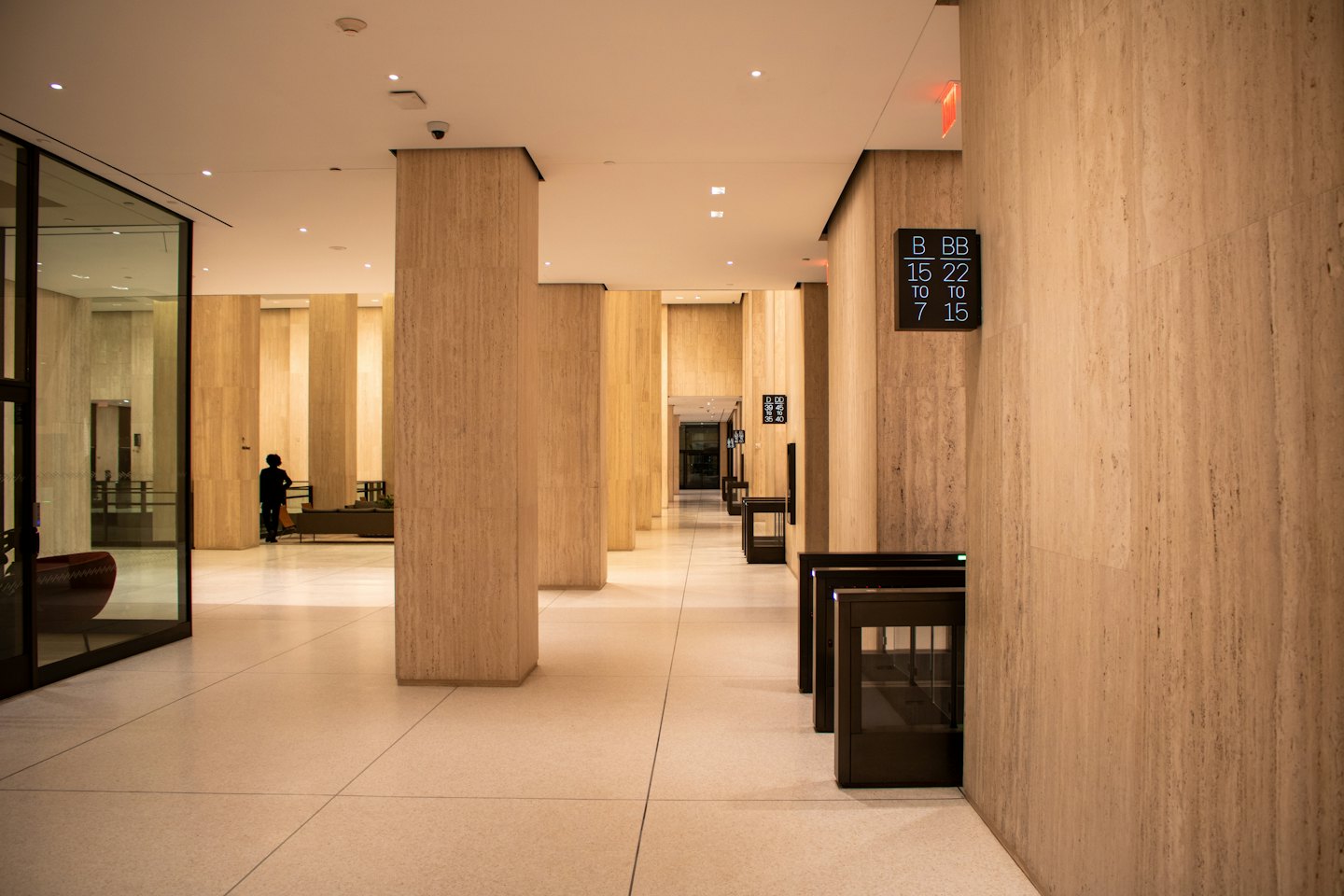 Moderne kantoorlobby met stenen pilaren en een silhouet van een persoon.